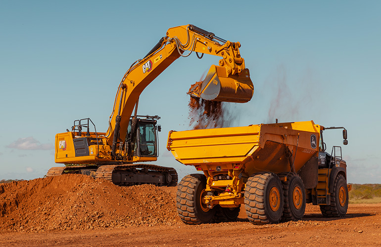 A Bedrock Robotics-equipped autonomous excavator loading a haul truck on a construction site