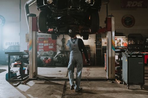 Mechanic working underneath a car raised on a lift in an auto repair shop