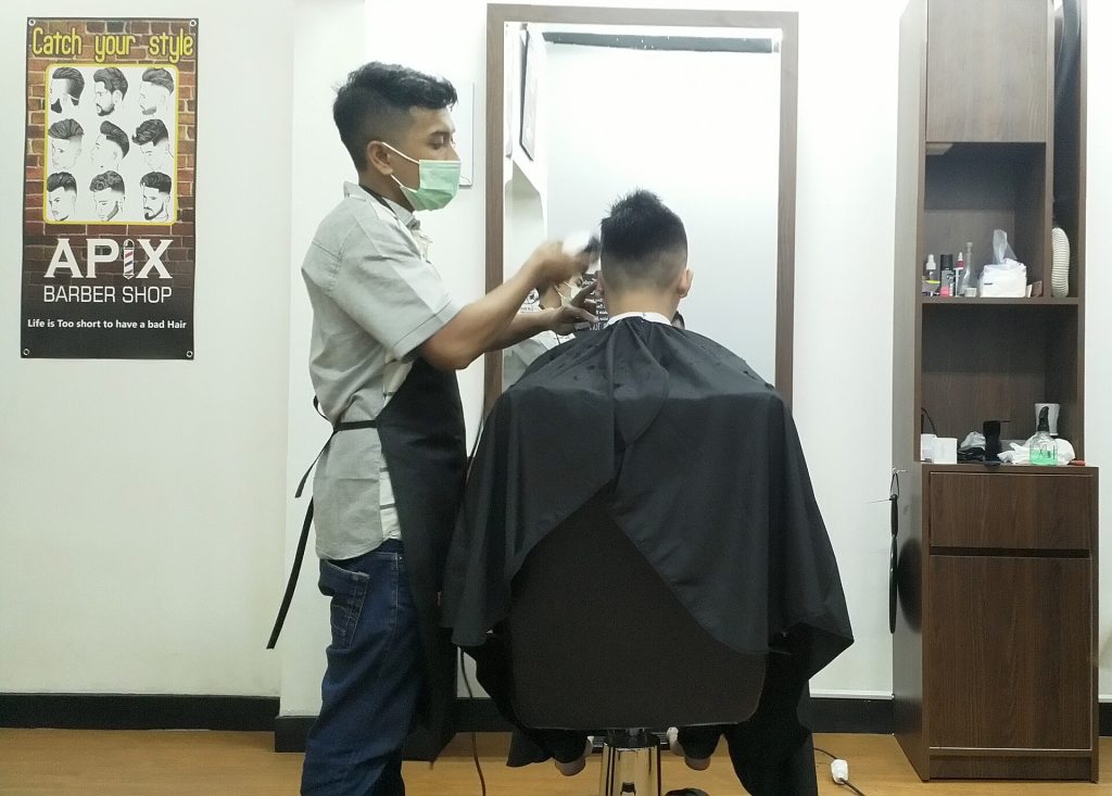 A barber cutting a client's hair in a barbershop