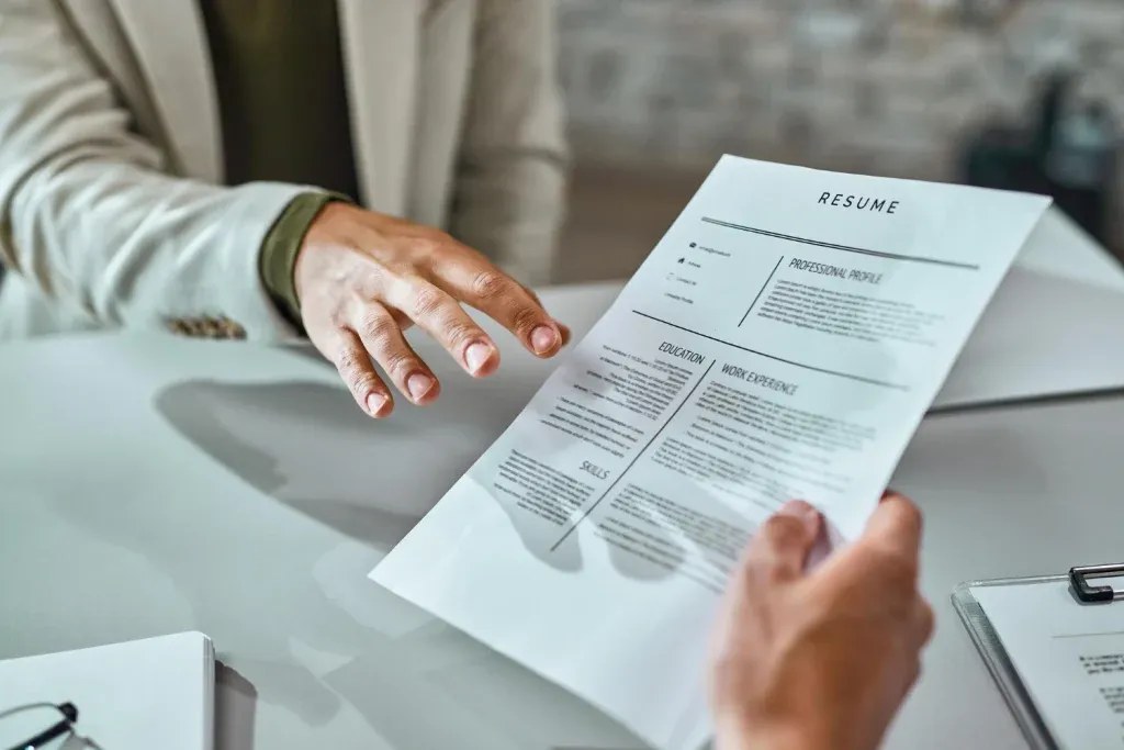 Printed resume being handed across a desk at a job interview