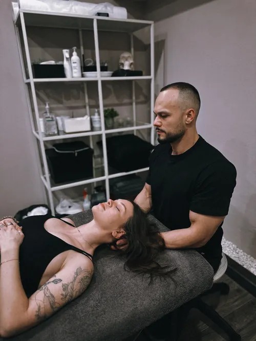 Chiropractor performing a neck adjustment on a patient lying on a treatment table