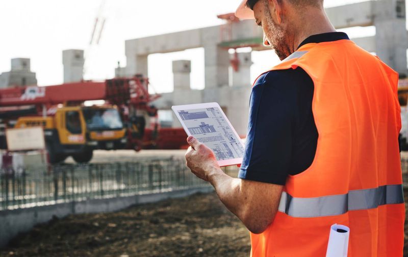 Construction contractor reviewing plans on a tablet at a job site