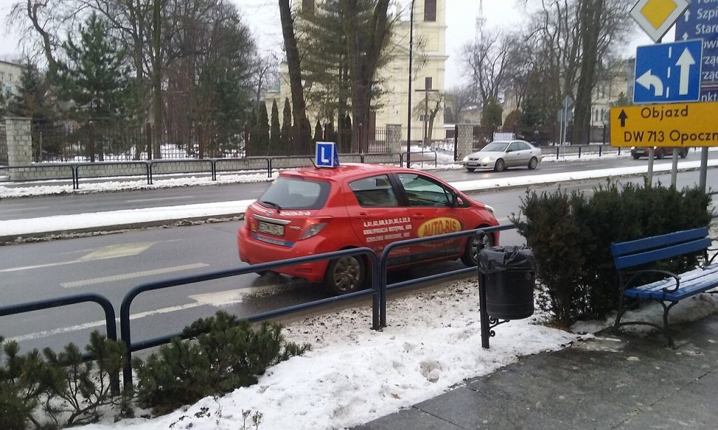 Red driving school car with an L plate on a street