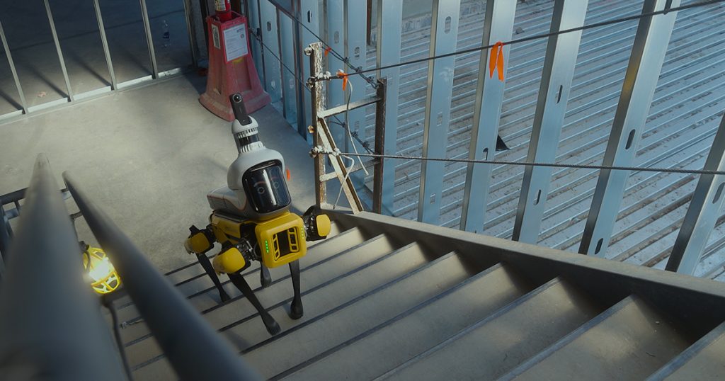 FieldAI quadruped robot climbing stairs at a construction site