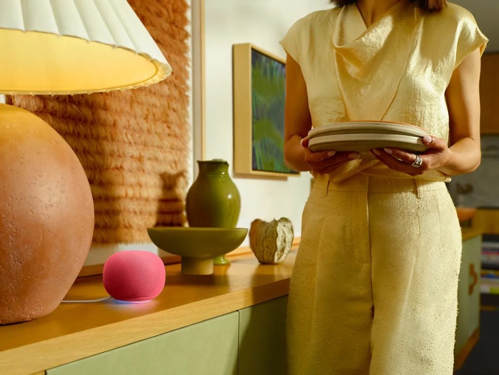 Google Home Speaker in Berry with its light ring glowing on a sideboard