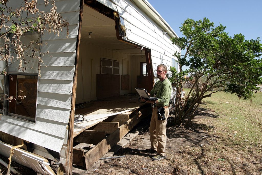Home inspector with a laptop examining a house exterior