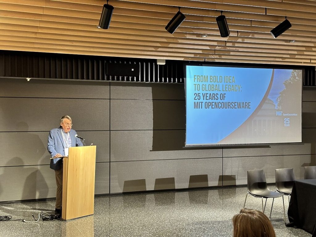 MIT OpenCourseWare 25th anniversary event — speaker at a podium in front of a screen reading 25 Years of MIT OpenCourseWare