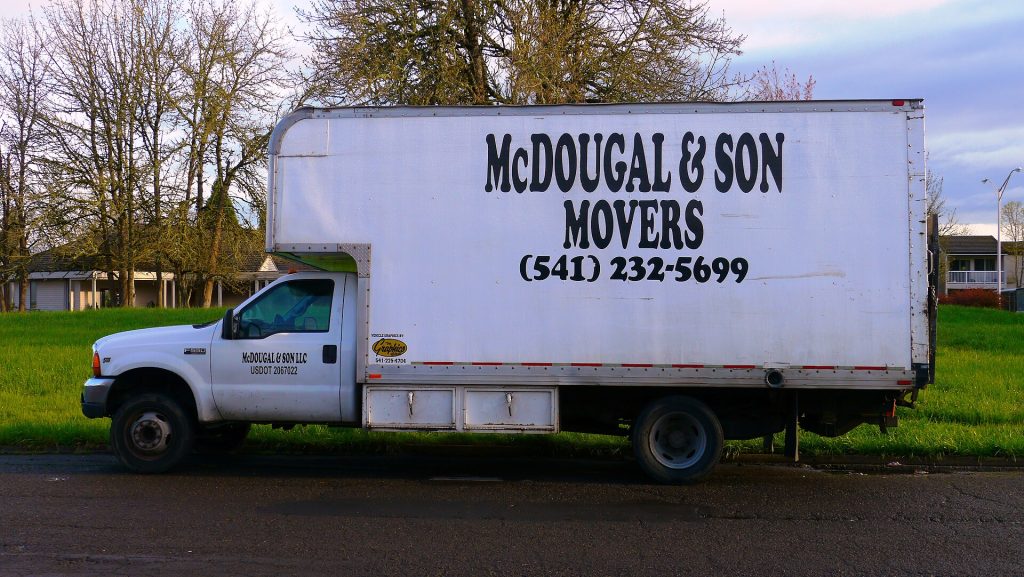 A moving company's box truck parked on a residential street