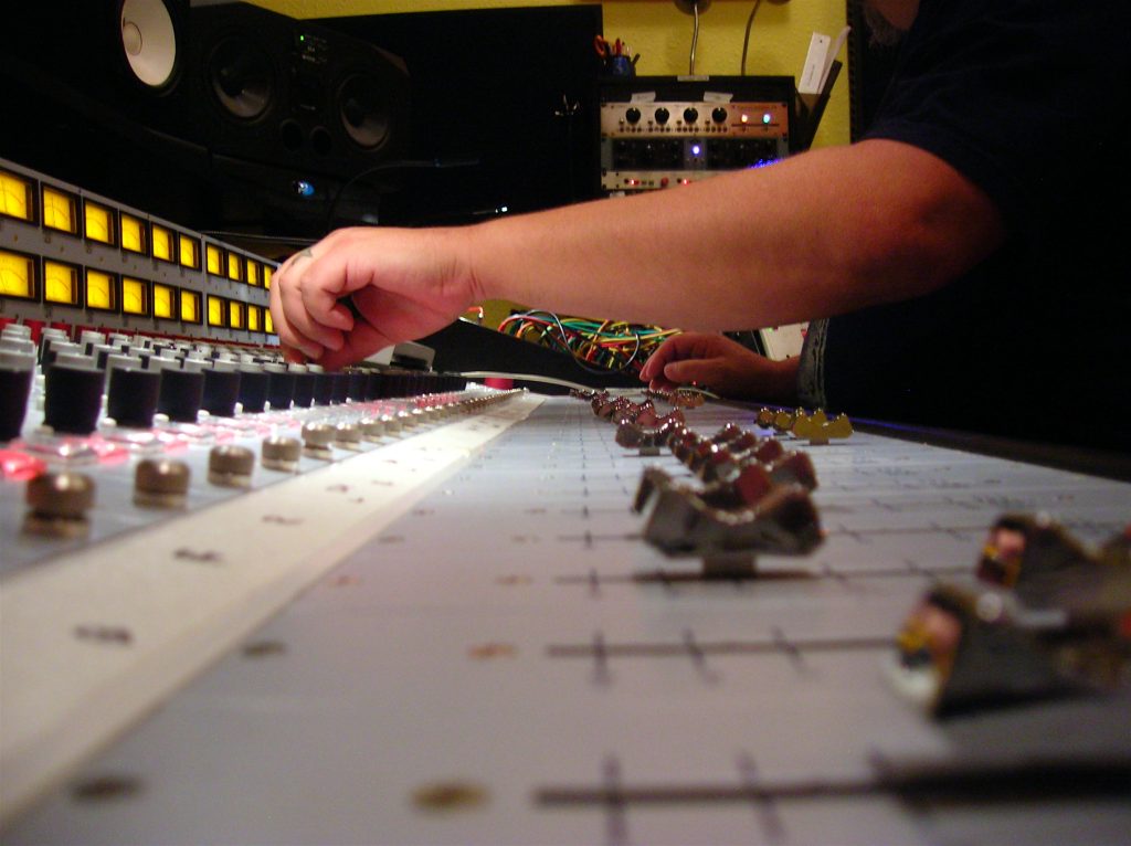 Audio engineer mixing a track on an analog console in a recording studio