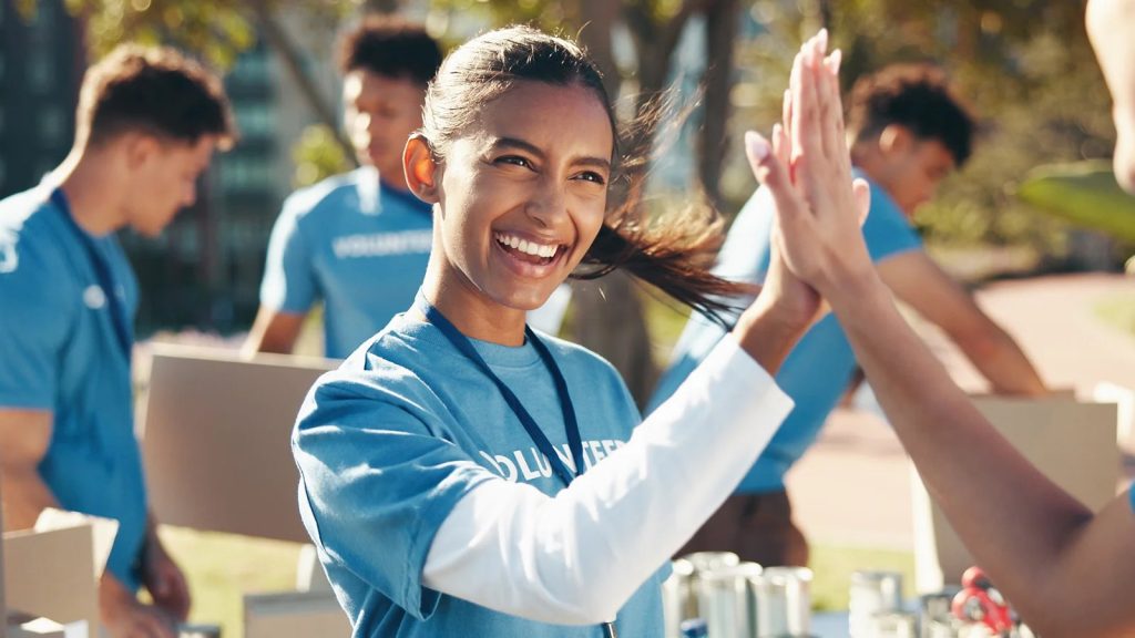 Nonprofit volunteers in blue shirts packing donation boxes outdoors