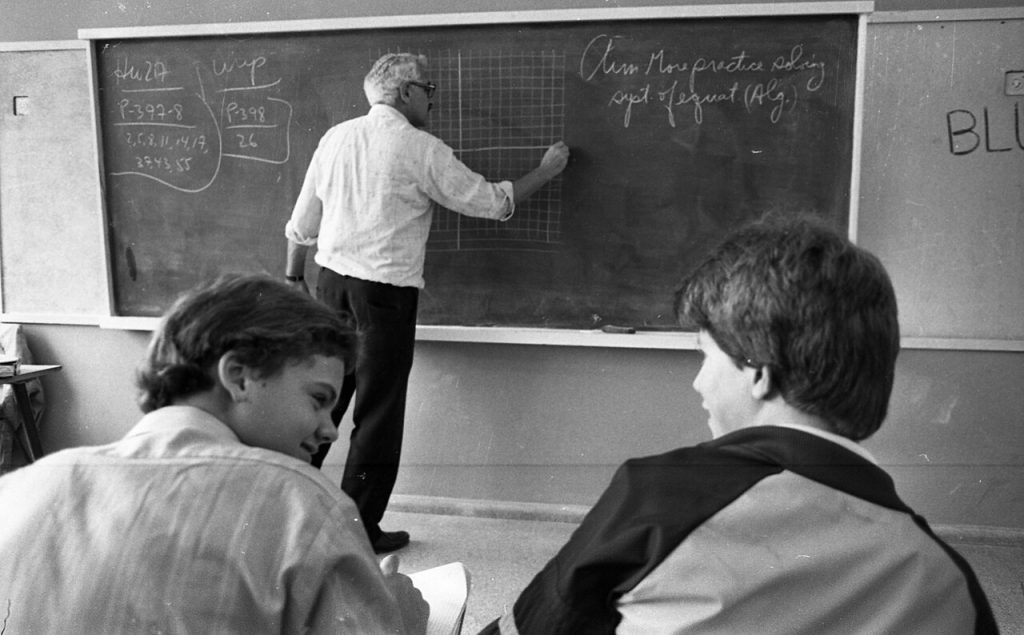 Teacher standing at a blackboard in a classroom