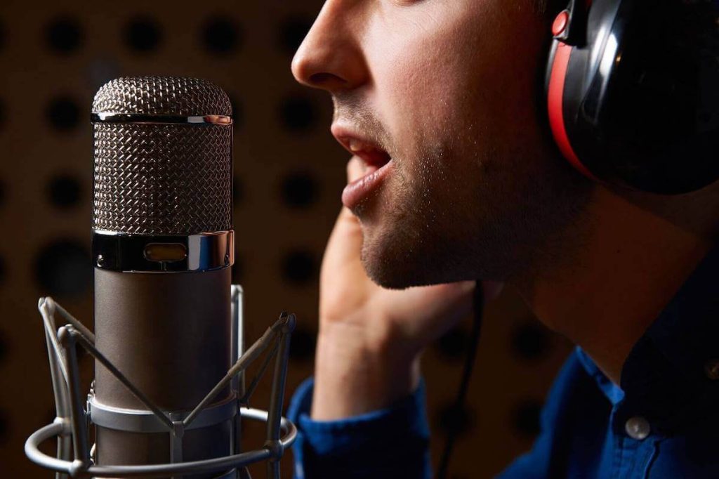 Voice actor recording at a studio condenser microphone wearing headphones